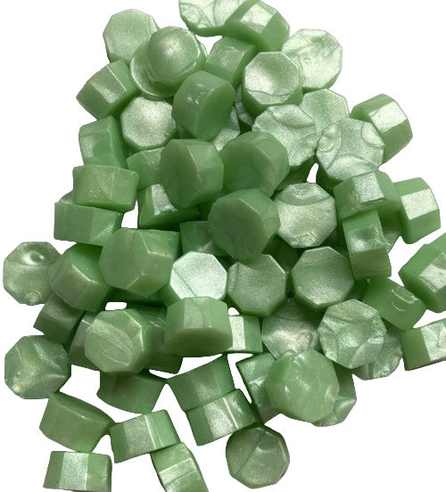 A heap of mint green pearl sealing wax beads on a white background.